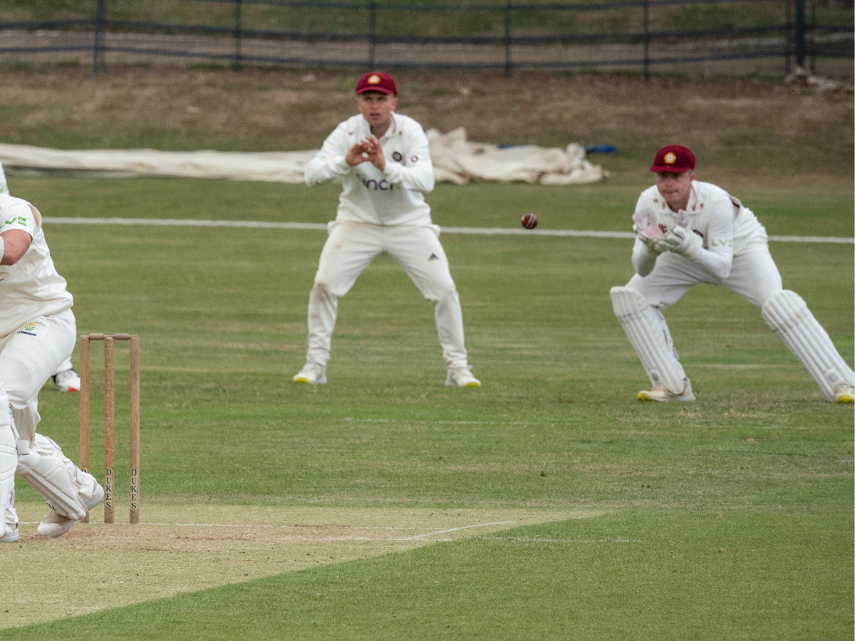 Cricket players attempting to catch a ball