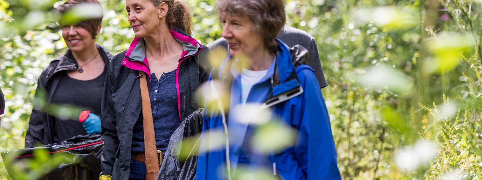 A group of women litter picking in a parkland scene