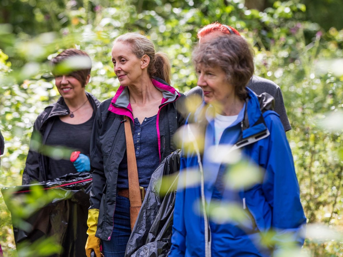 A group of women litter picking in a parkland scene
