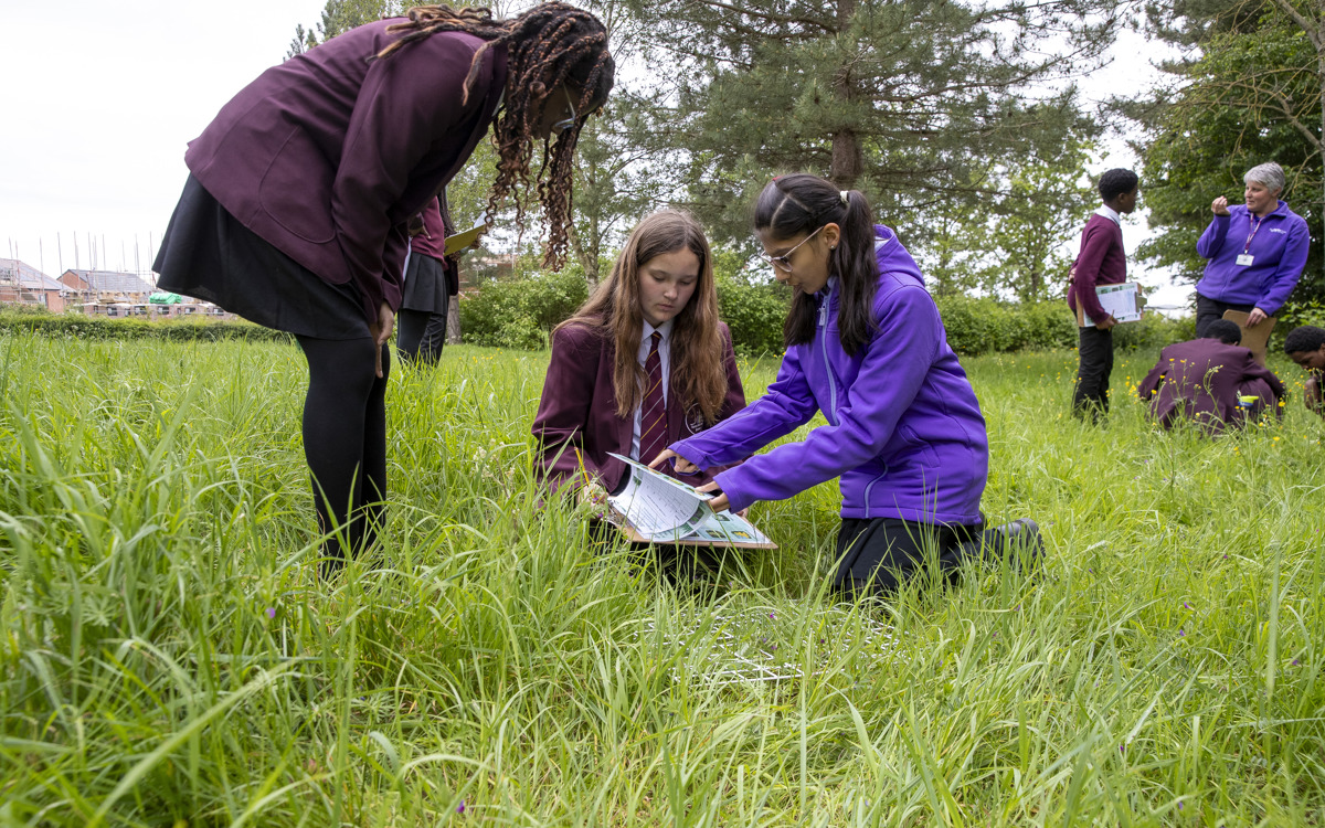 A group of students outside,  one with a clipboard