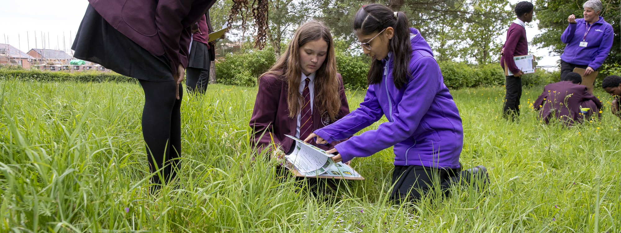 A group of students outside,  one with a clipboard