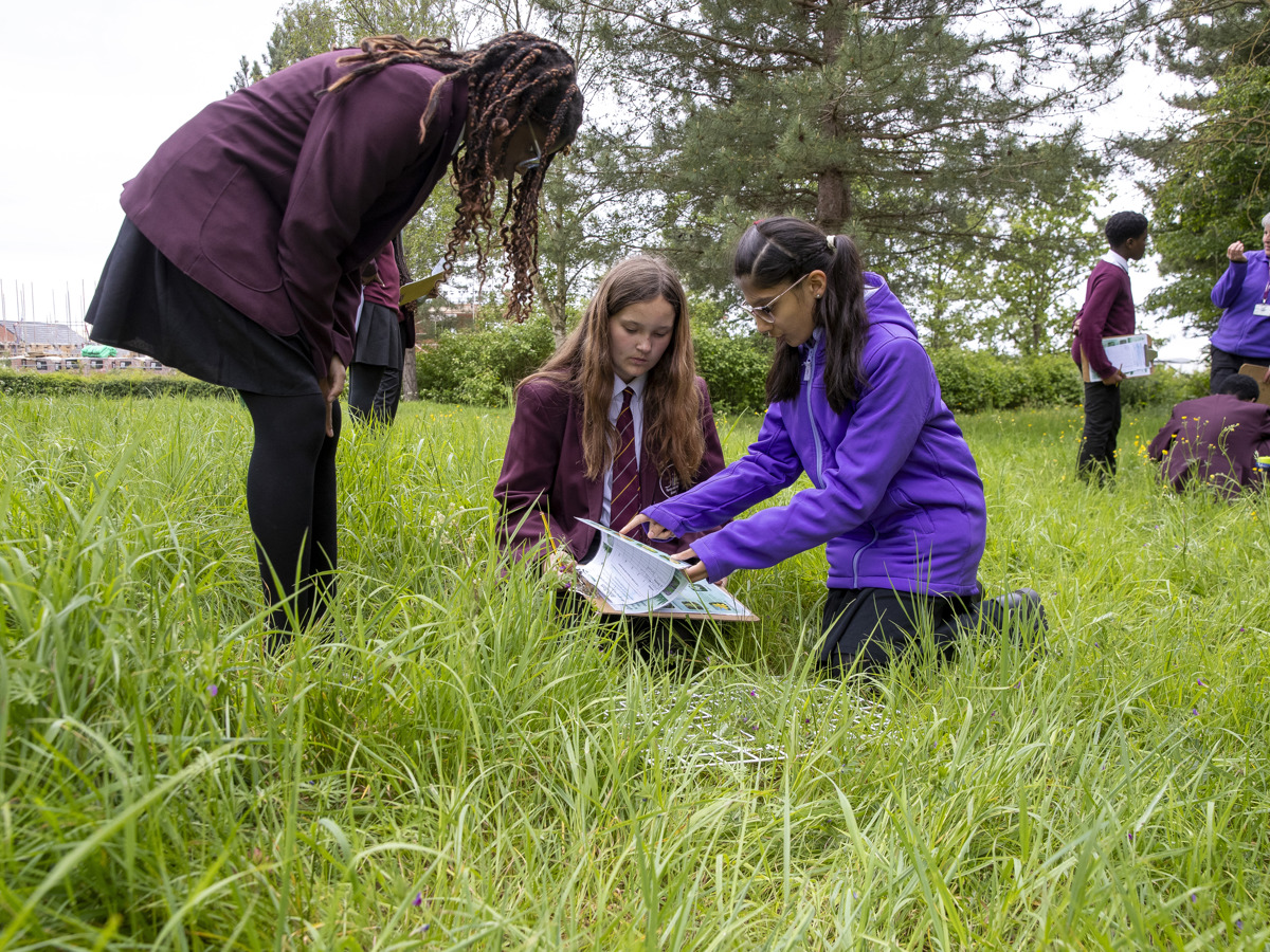 A group of students outside,  one with a clipboard