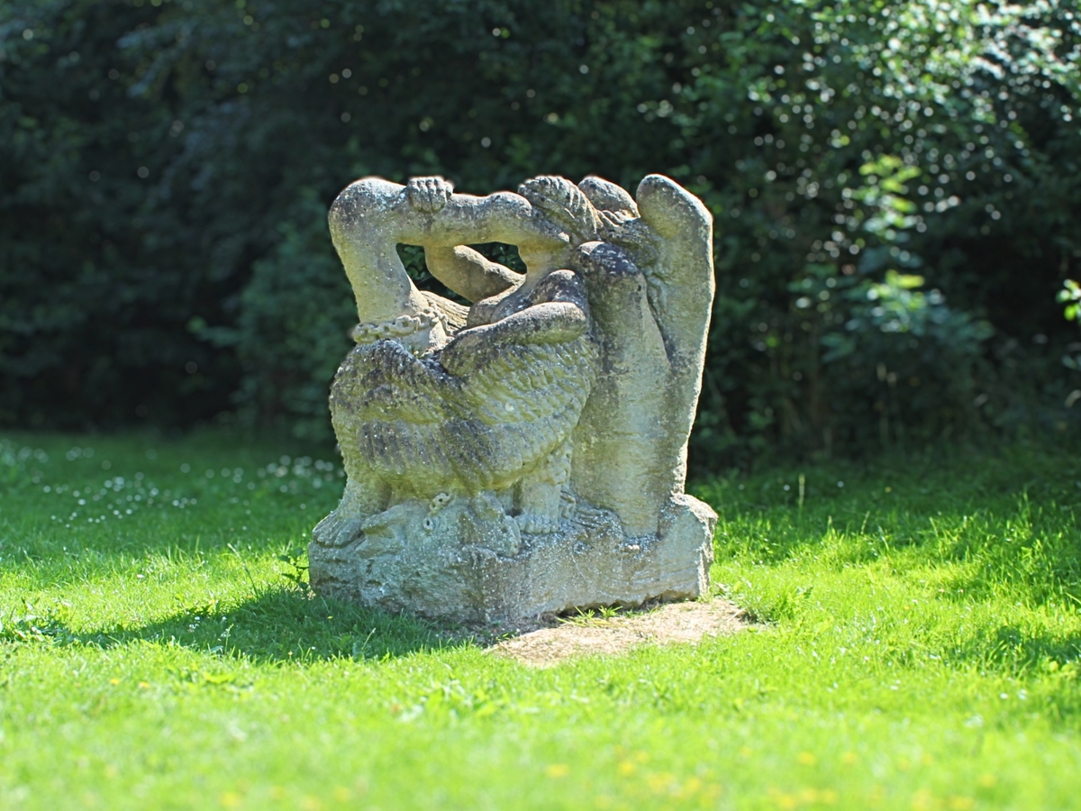 an almost square rock with a swan and person carved into it