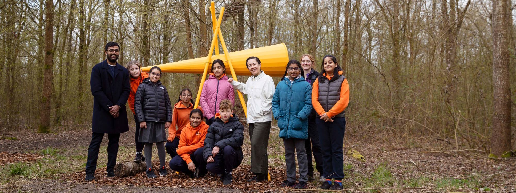 Group of adults and children in woodland with large listening cone