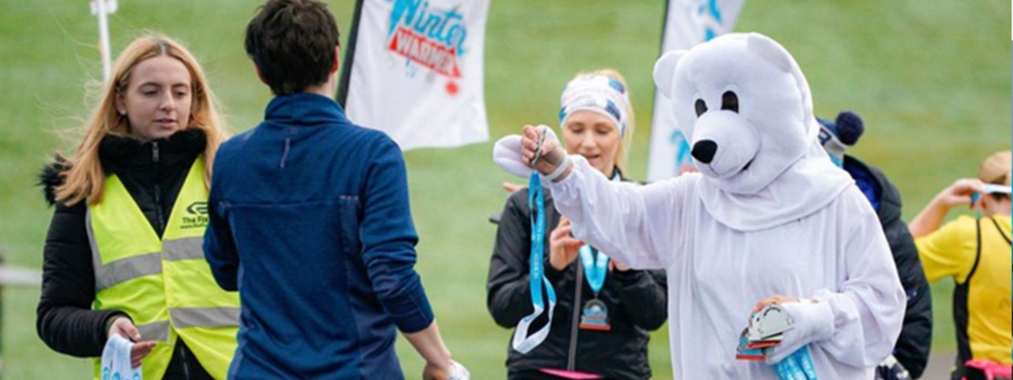 White bear mascot giving medals to runners  