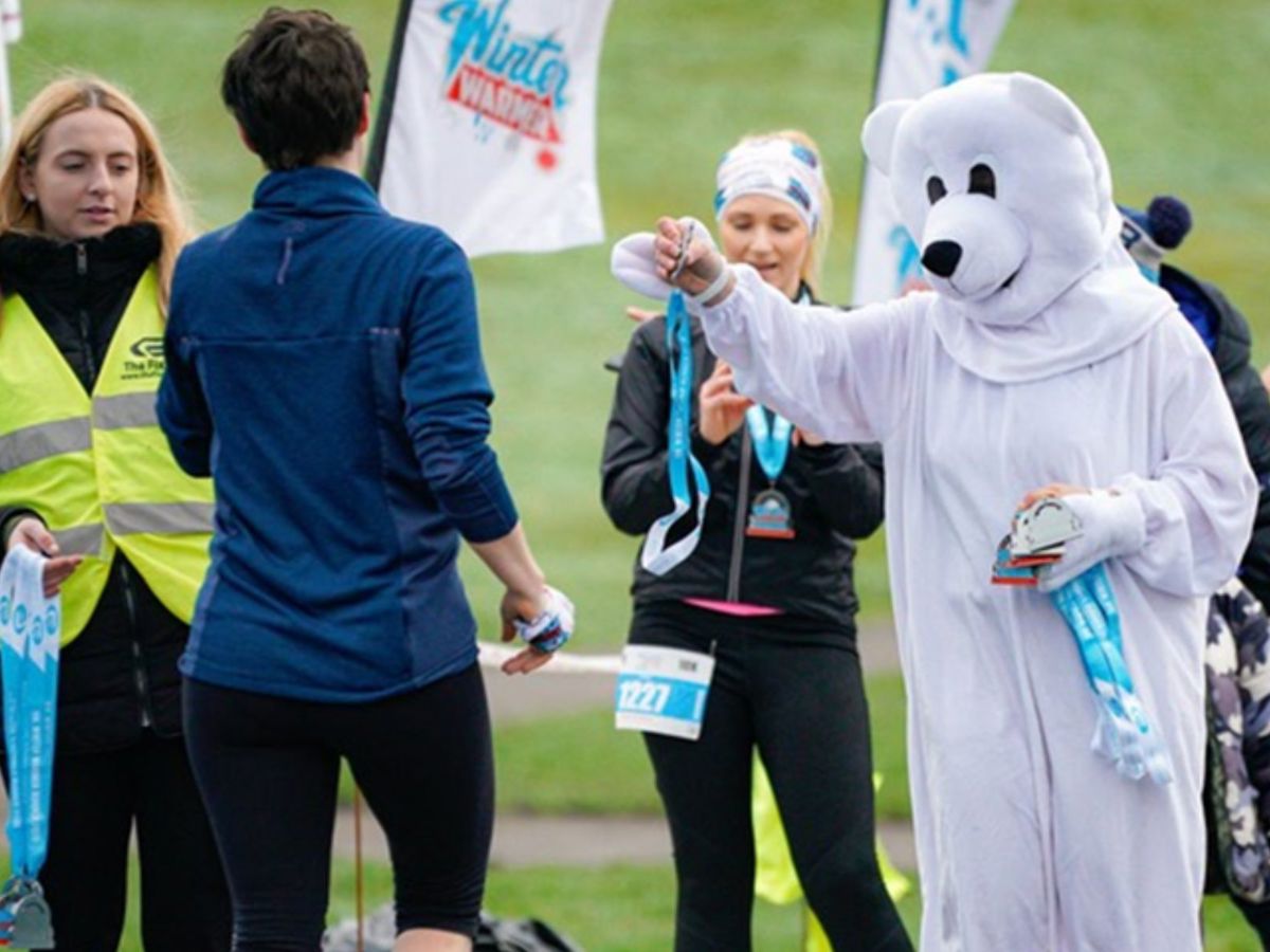 White bear mascot giving medals to runners  