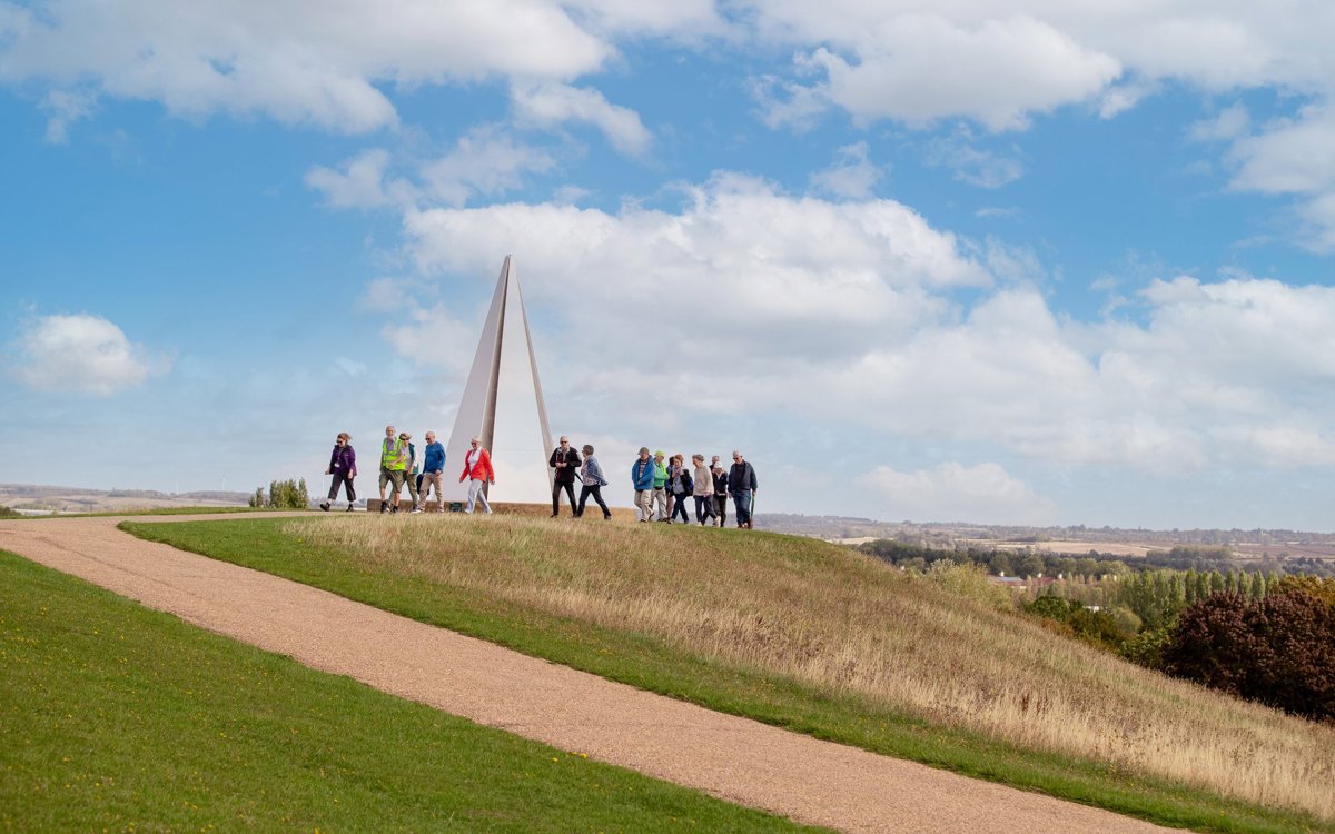 Group of walkers at Light Pyramid at the top of Campbell Park with views across Milton Keynes in the distance