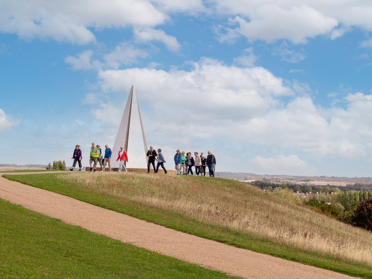 Group of walkers at Light Pyramid at the top of Campbell Park with views across Milton Keynes in the distance