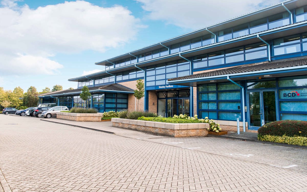 Parking area and view of the exterior brick building with blue framed doors and windows