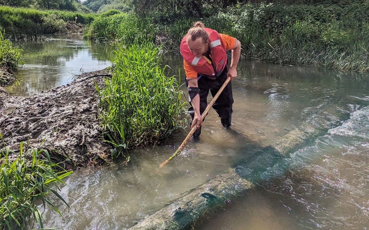 Team member next to digger log