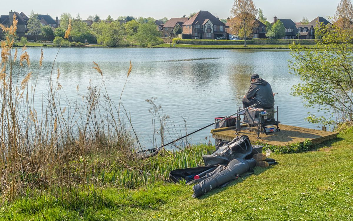 person sat down at a lake with their fishing gear