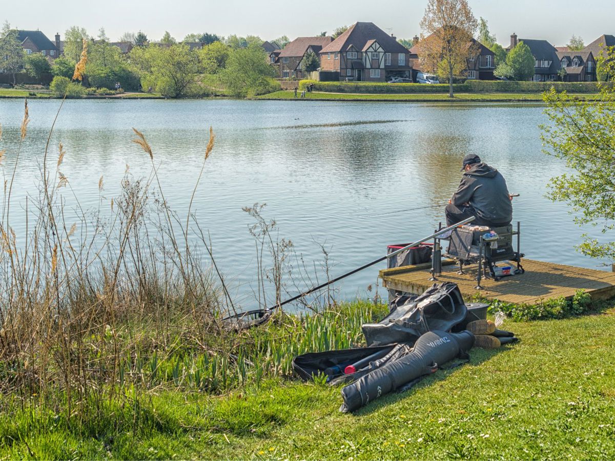 person sat down at a lake with their fishing gear