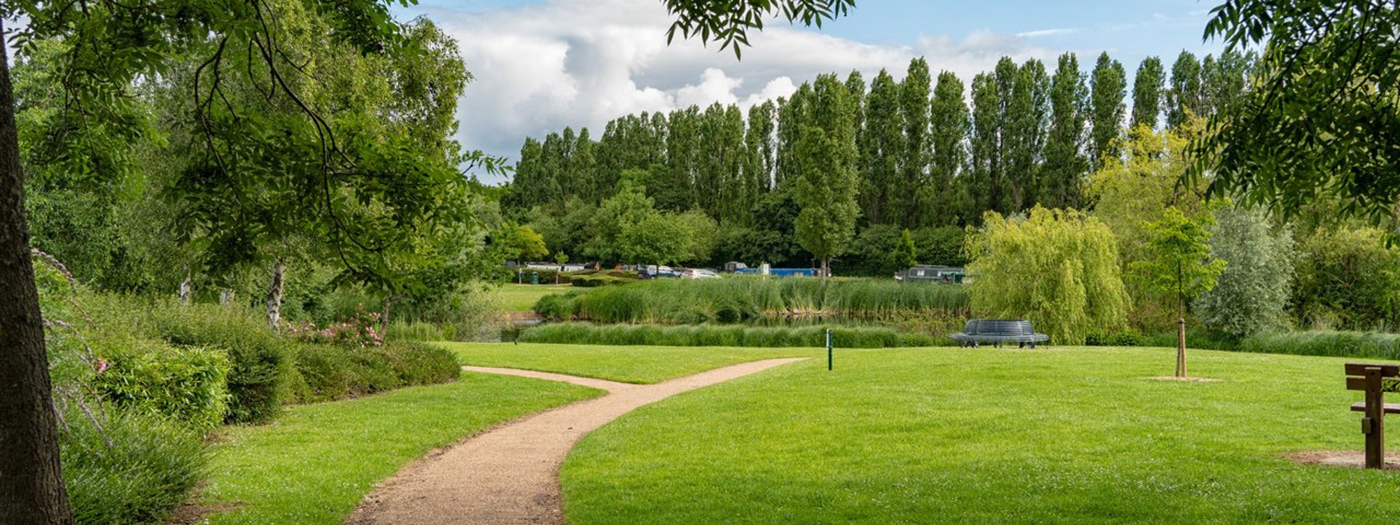 Green space by the canal, on a sunny day with scattered clouds