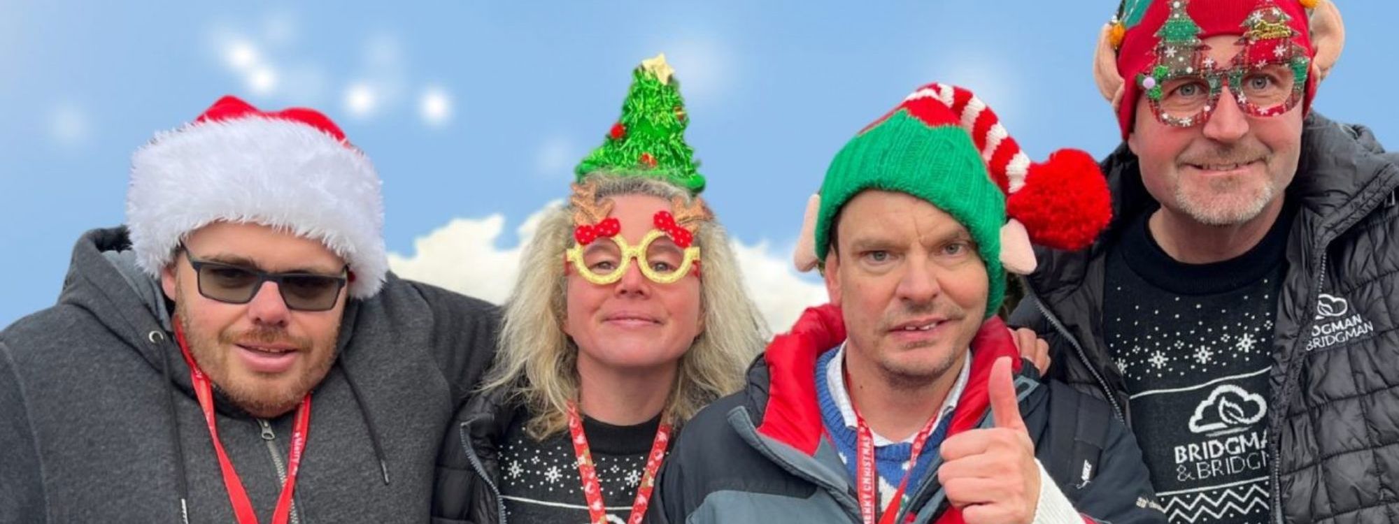 Four people with Christmas hats and jumpers with blue background