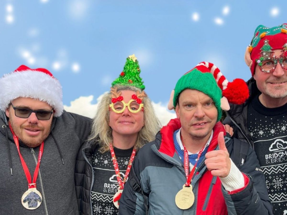 Four people with Christmas hats and jumpers with blue background