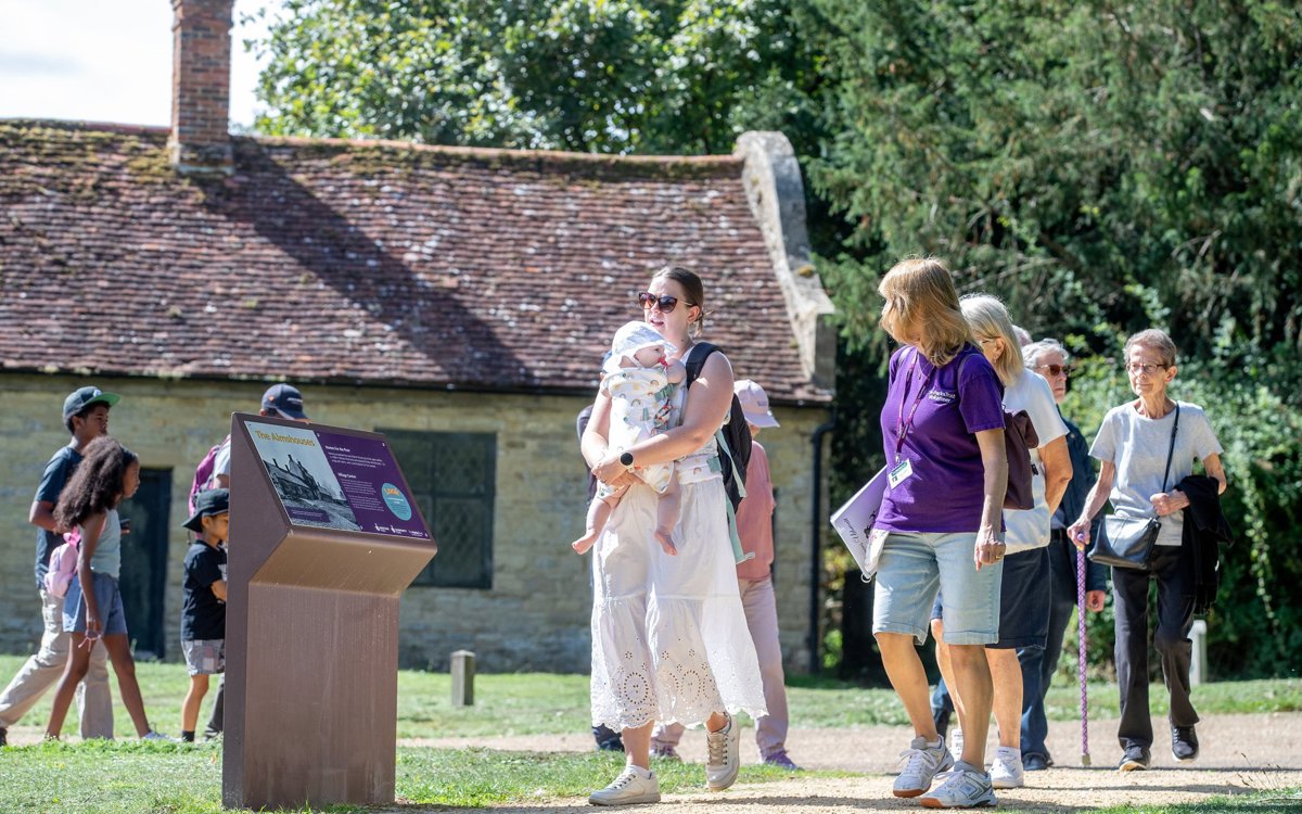 Group of people on a guided walk with almshouses behind