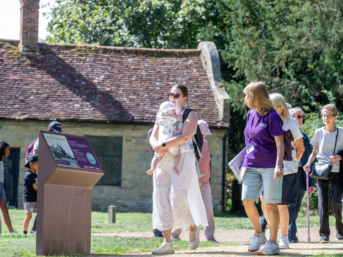 Group of people on a guided walk with almshouses behind