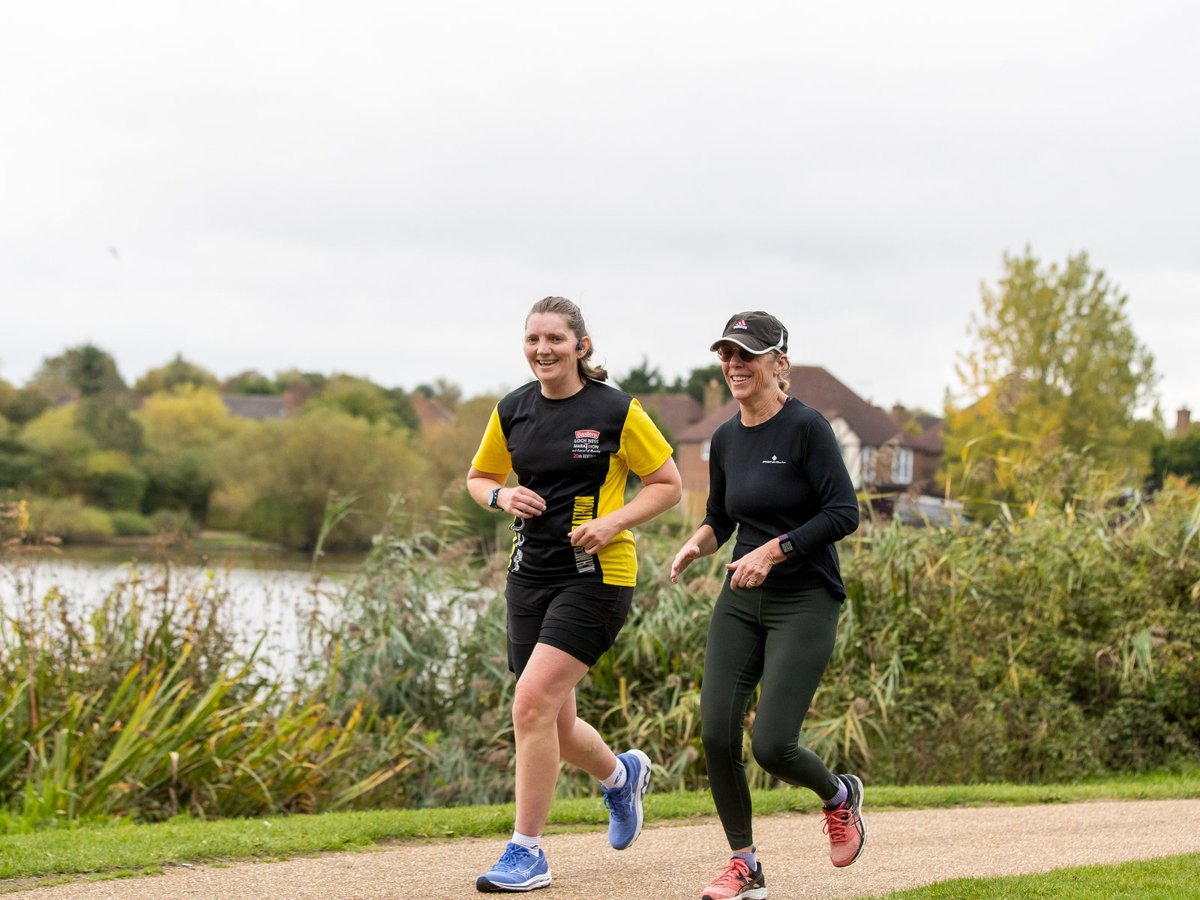 Two smiling female runners with Furzton Lake in the background