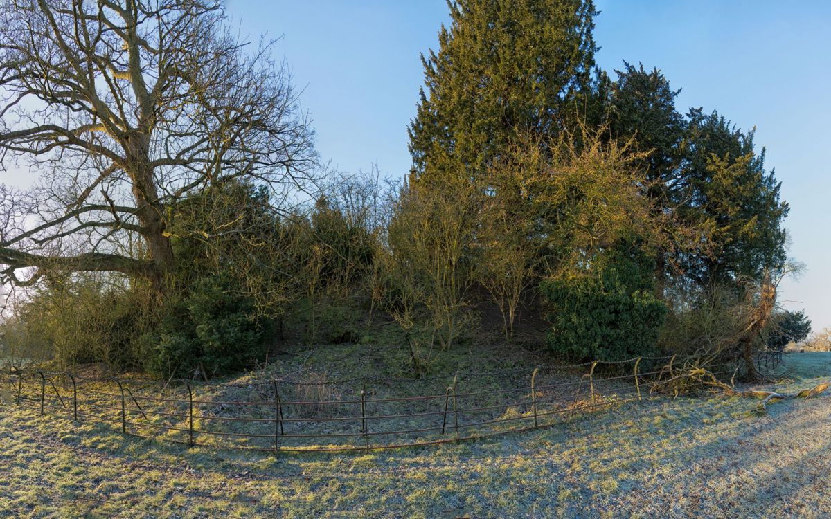 Mound of earth with trees on it, surrounded by a fence