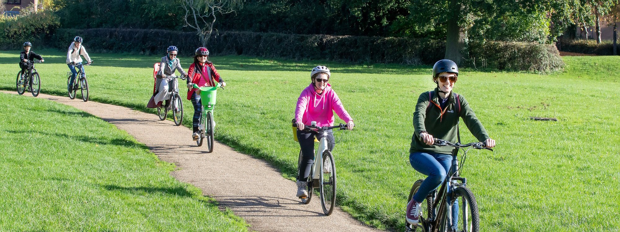 Group cycling through parkland on path