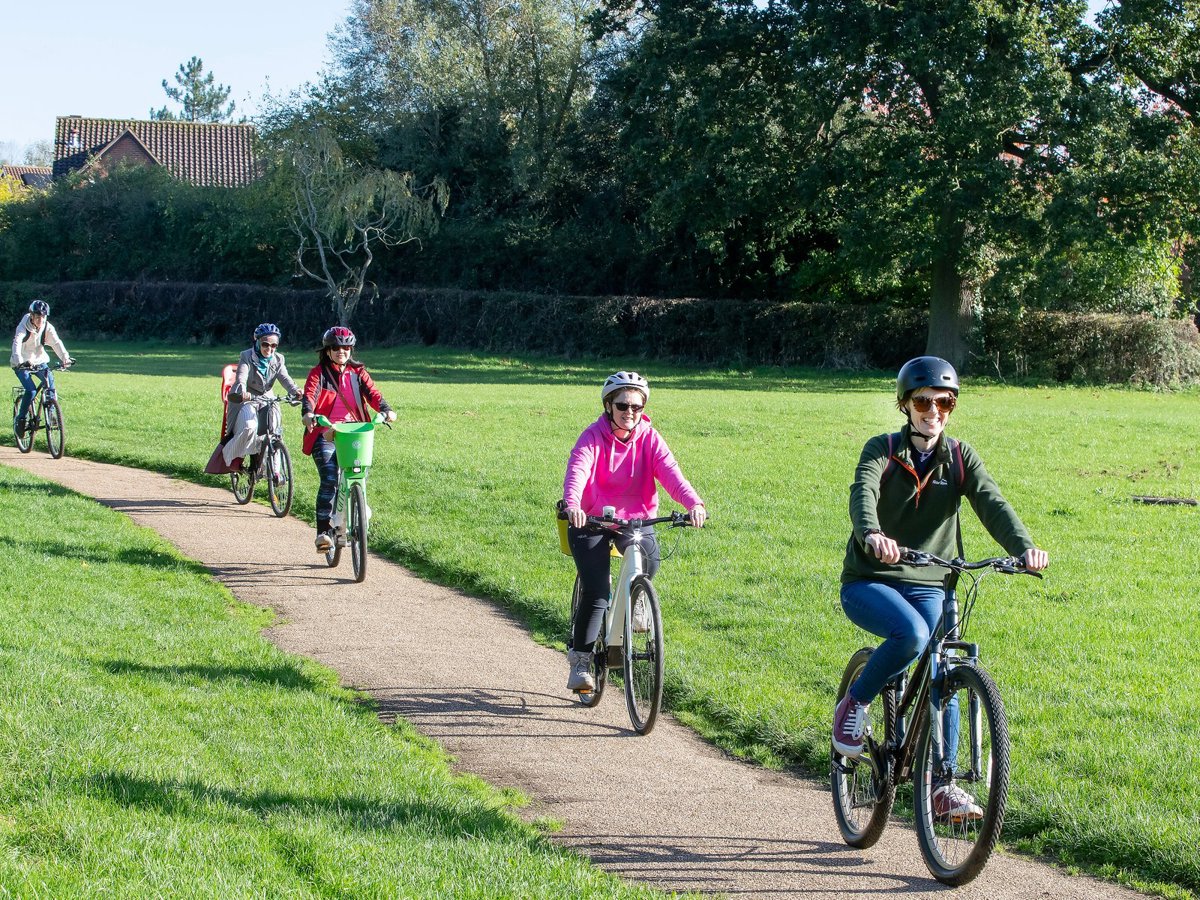 Group cycling through parkland on path