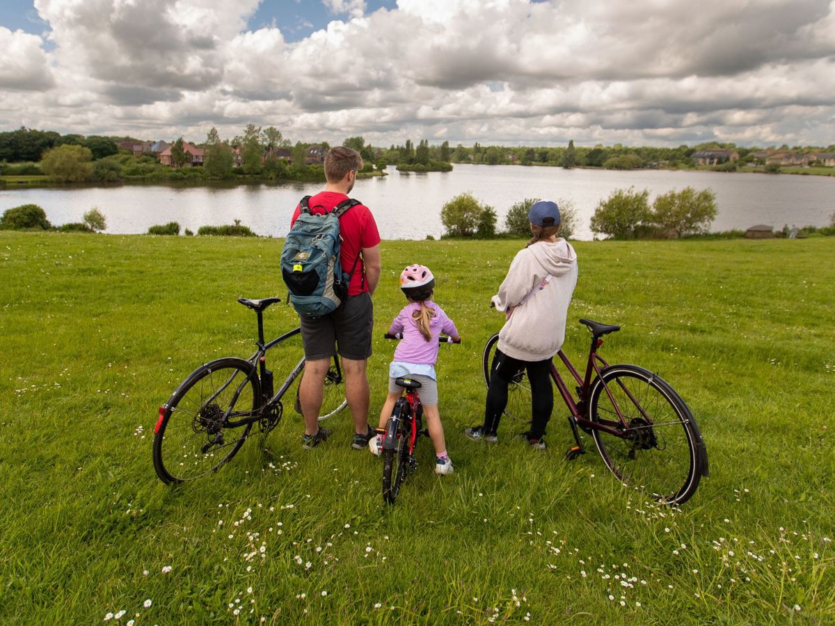 A family on bikes facing towards Furzton Lake