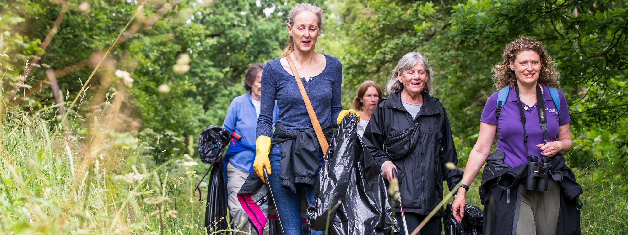 A group of women litter picking in a parkland scene