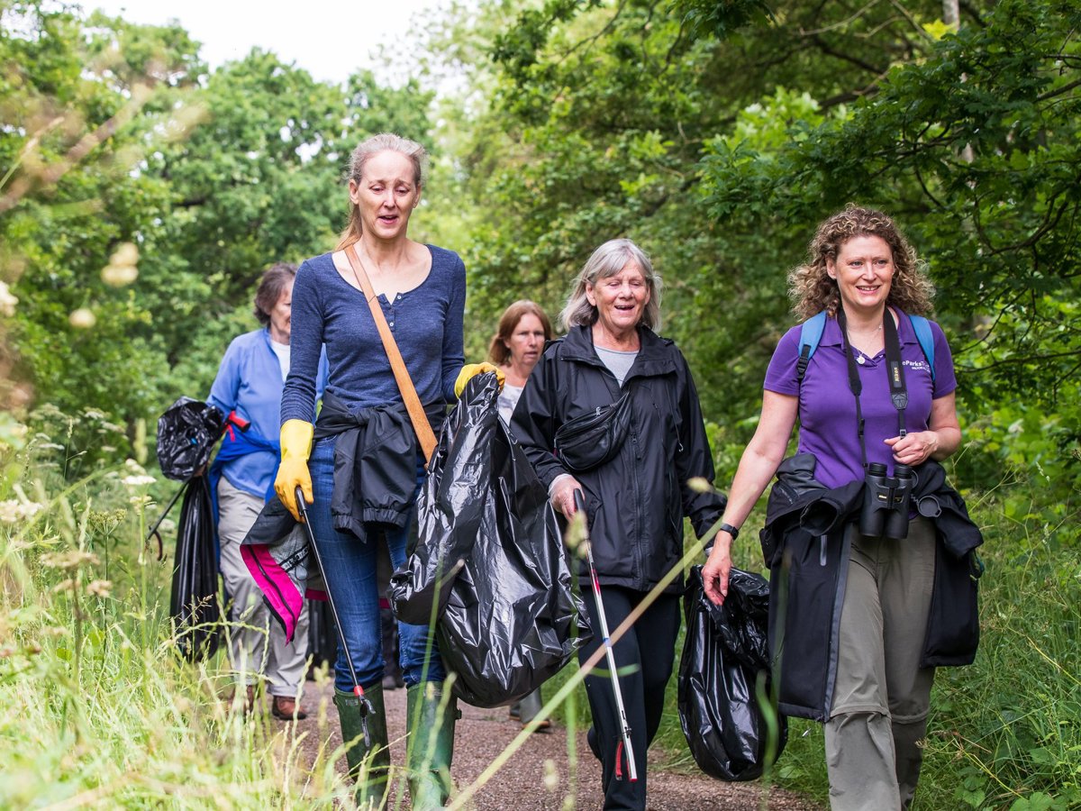 A group of women litter picking in a parkland scene