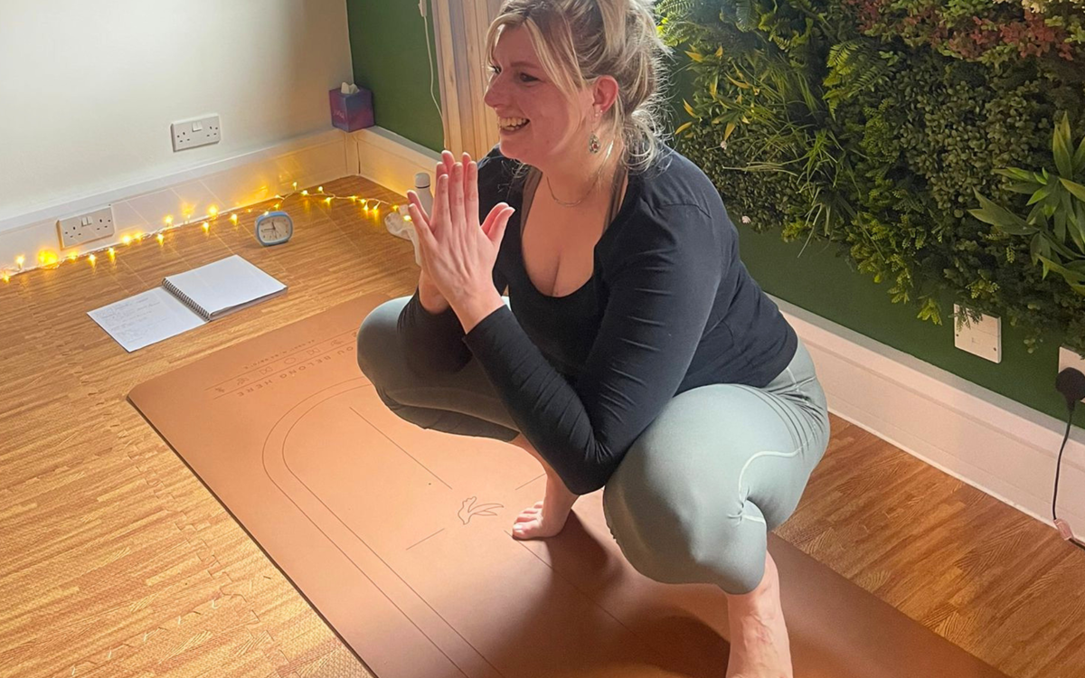 A therapist leads a class, posing with their hands palm to palm.