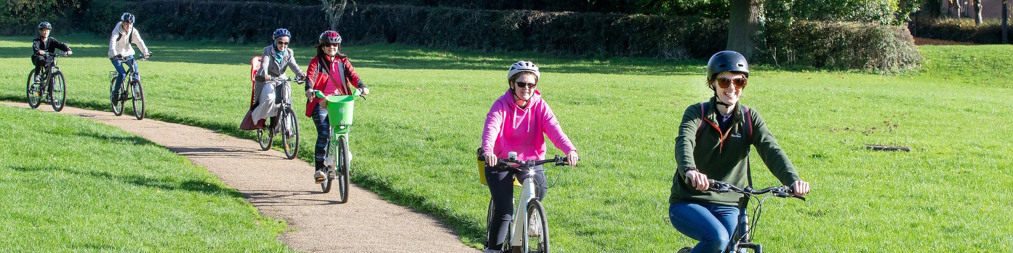 Female cyclists in a green parkland scene