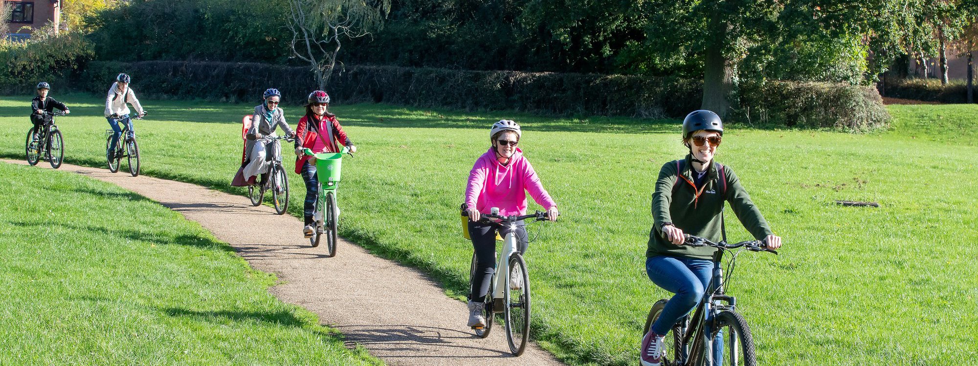 Female cyclists in a green parkland scene