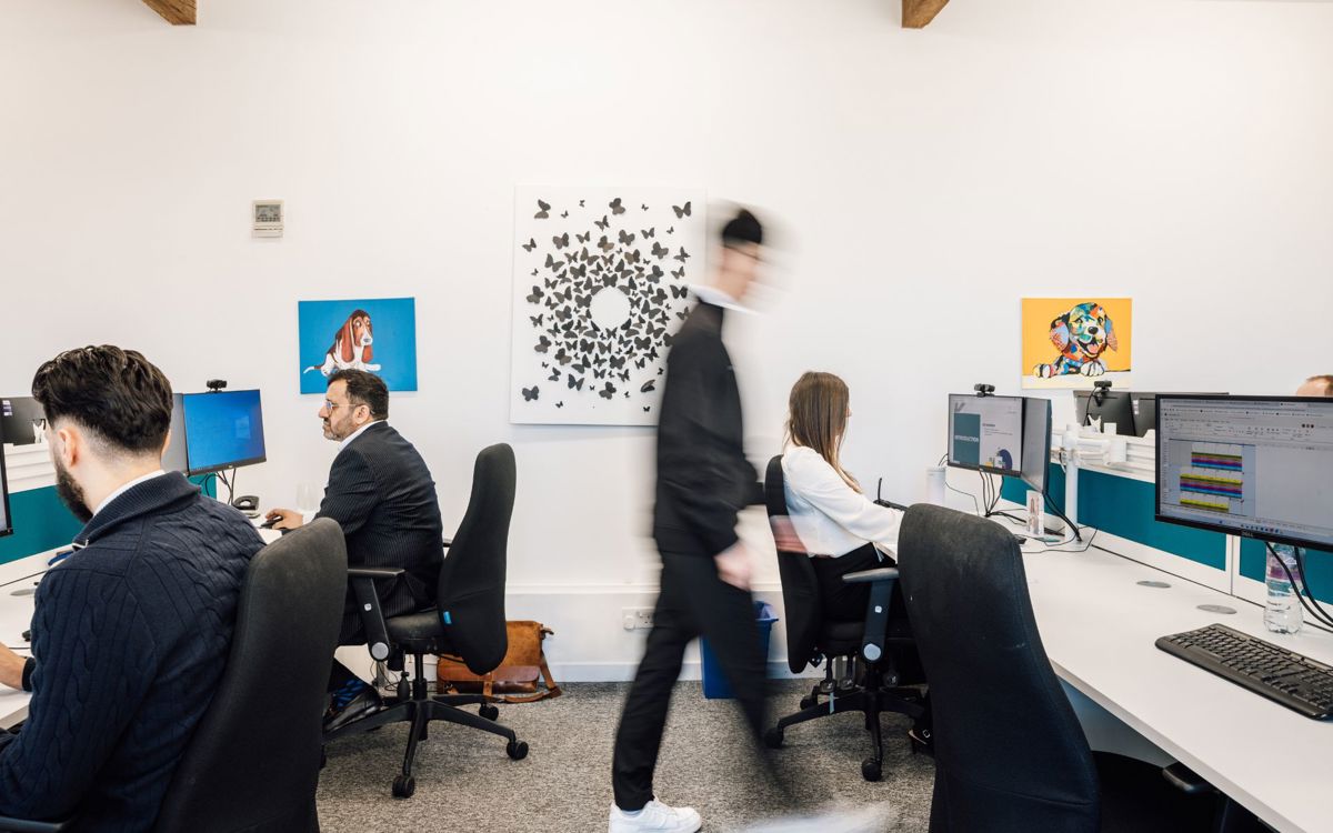 People sat at desks and person walking through office