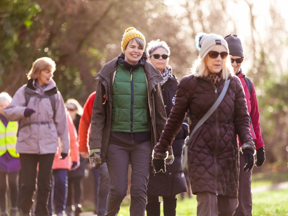 A group of women walking in a parkland scene. 