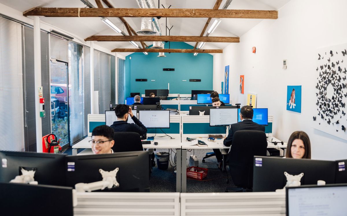 Ad Valorem Team sat working at desks in office with wooden beams on ceiling