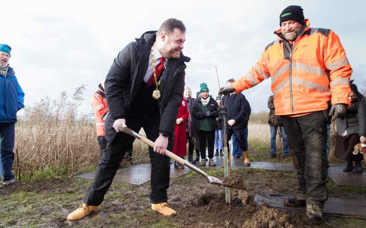 Mayor of Milton Keynes James Lancaster planting a tree next to Parks Trust staff member in orange uniform