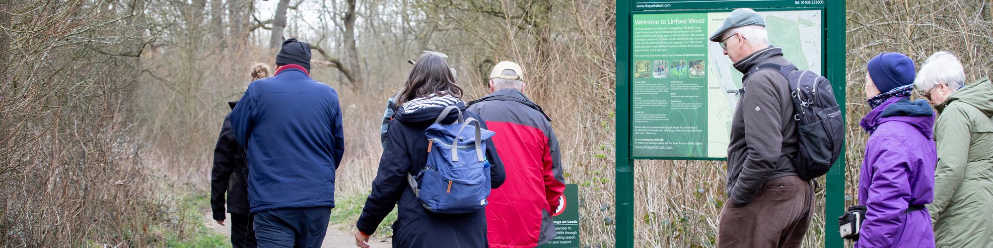 Group walking into woodland with Linford Wood sign