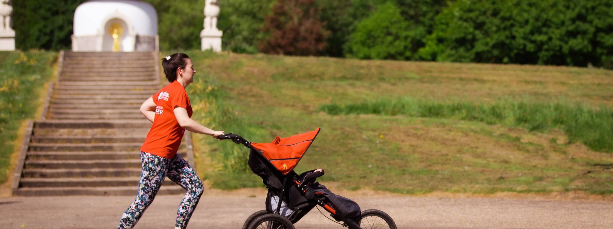 A female runner pushing a running buggy in front of the Peace Pagoda at Willen Lake