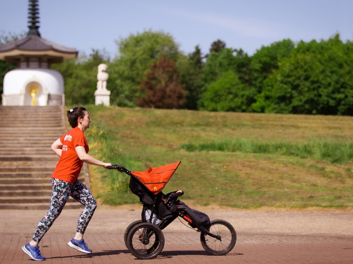 A female runner pushing a running buggy in front of the Peace Pagoda at Willen Lake