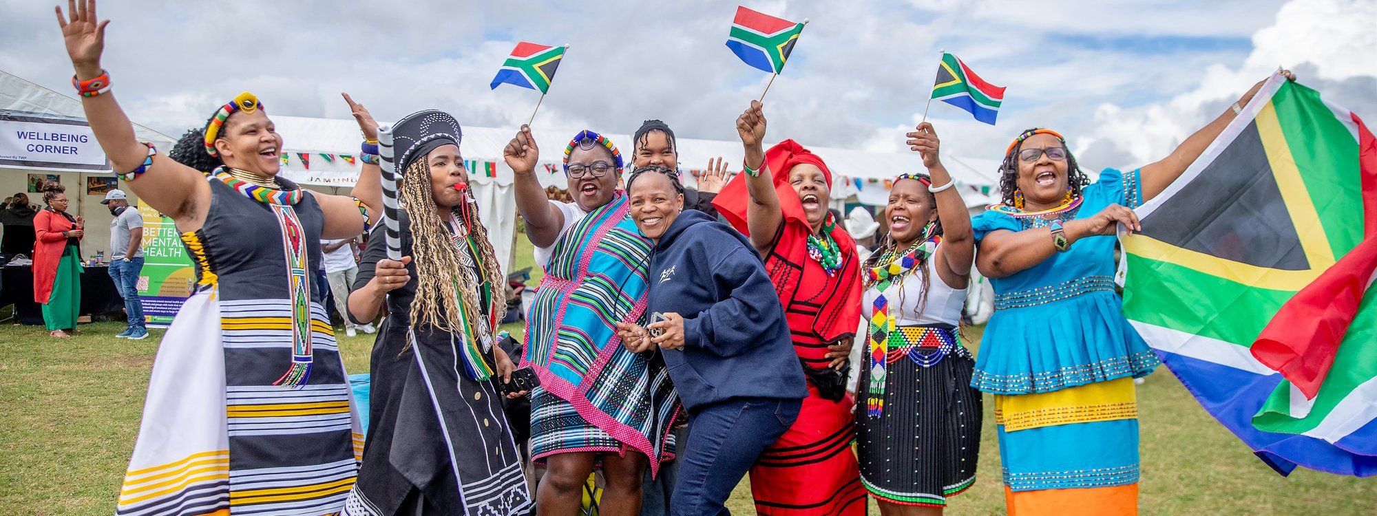 group of people in colourful attire holding South African flags 