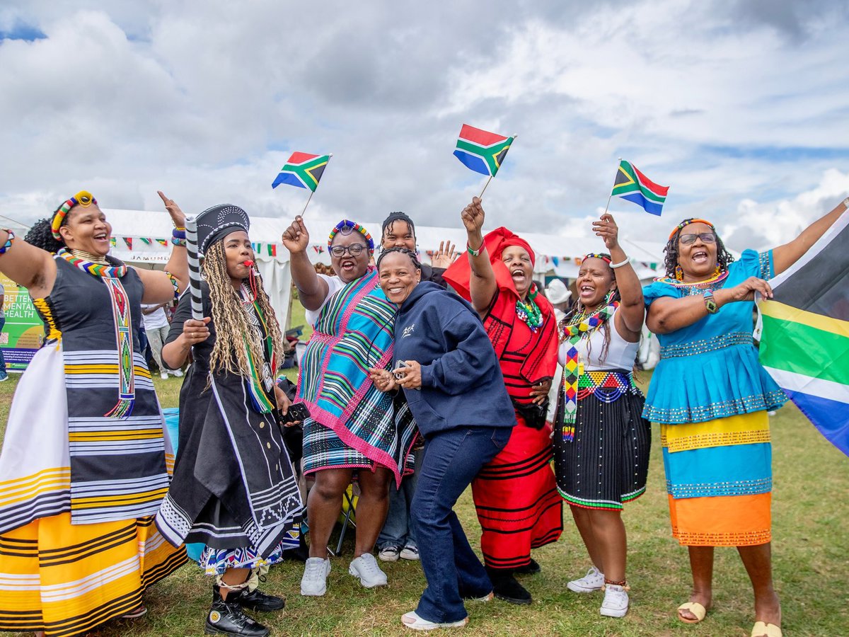 group of people in colourful attire holding South African flags 
