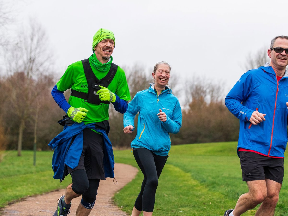 Two male and a female runner in a parkland area