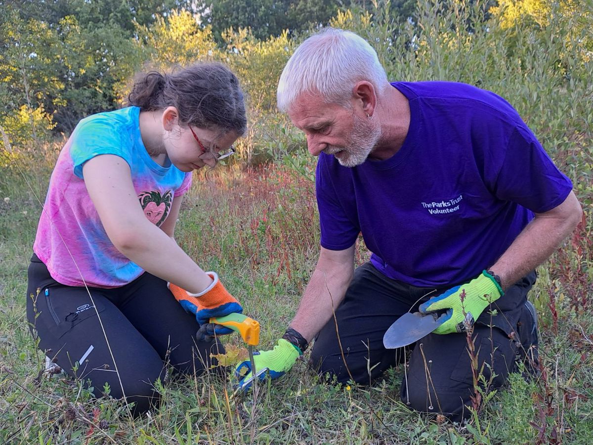Volunteer helping a child at an outdoor learning session in the park
