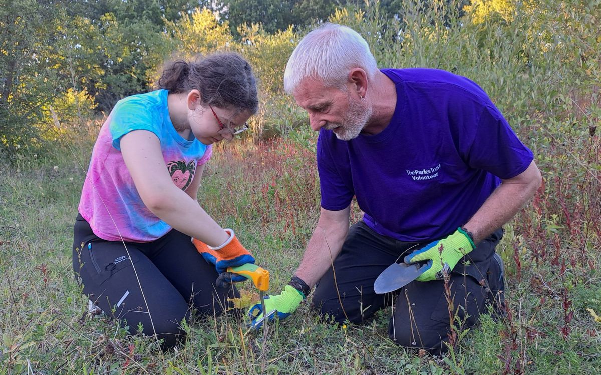 Volunteer helping a child at an outdoor learning session in the park