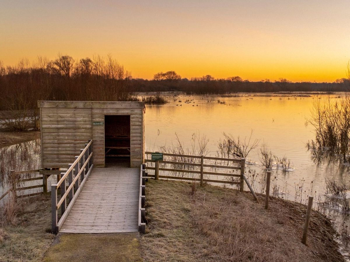 Sunset behind bird hide overlooking lake