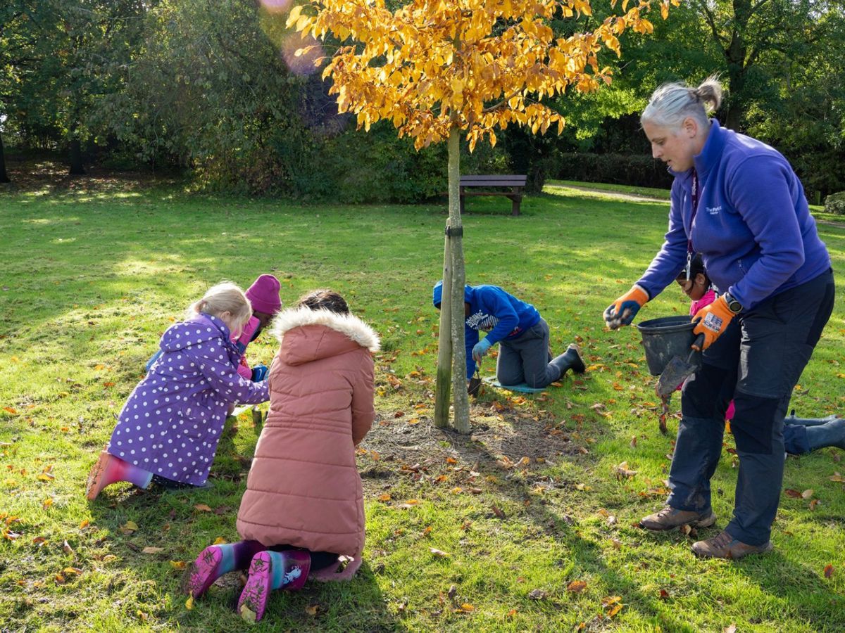 Children planting bulbs in the park with The Parks Trust outdoor learning leader