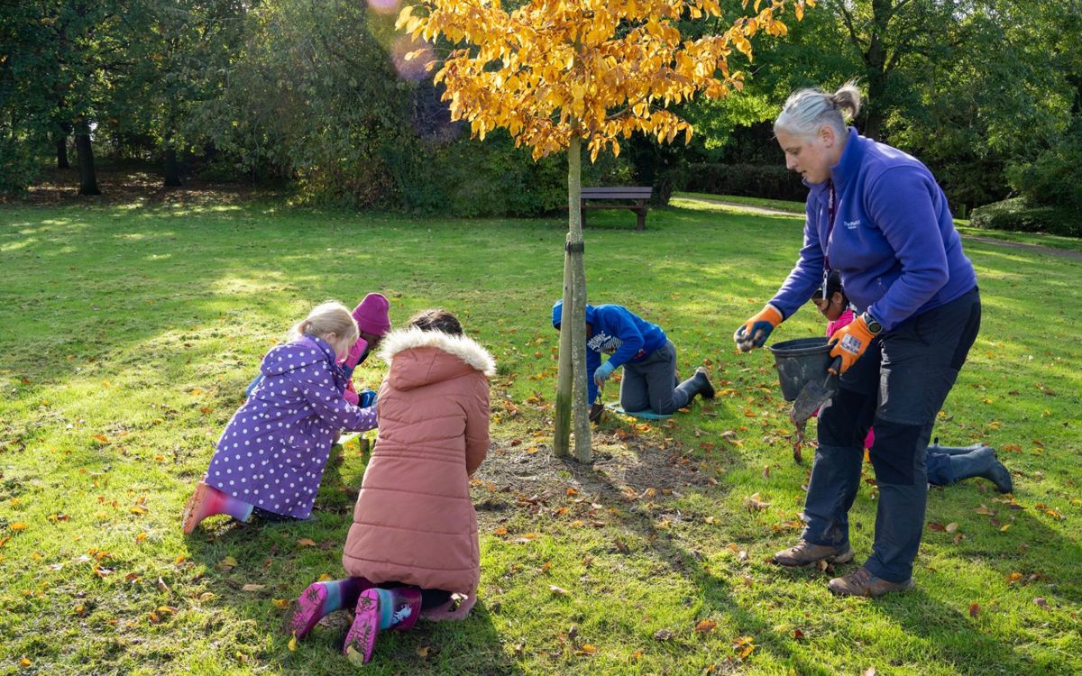 Children planting bulbs in the park with The Parks Trust outdoor learning leader