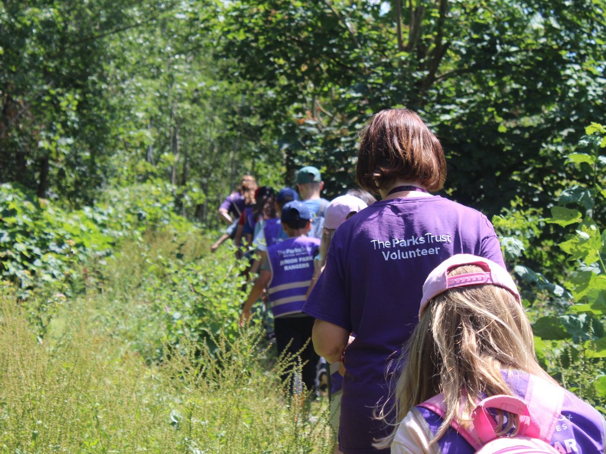 Volunteer in purple t'shirt walking through park with children