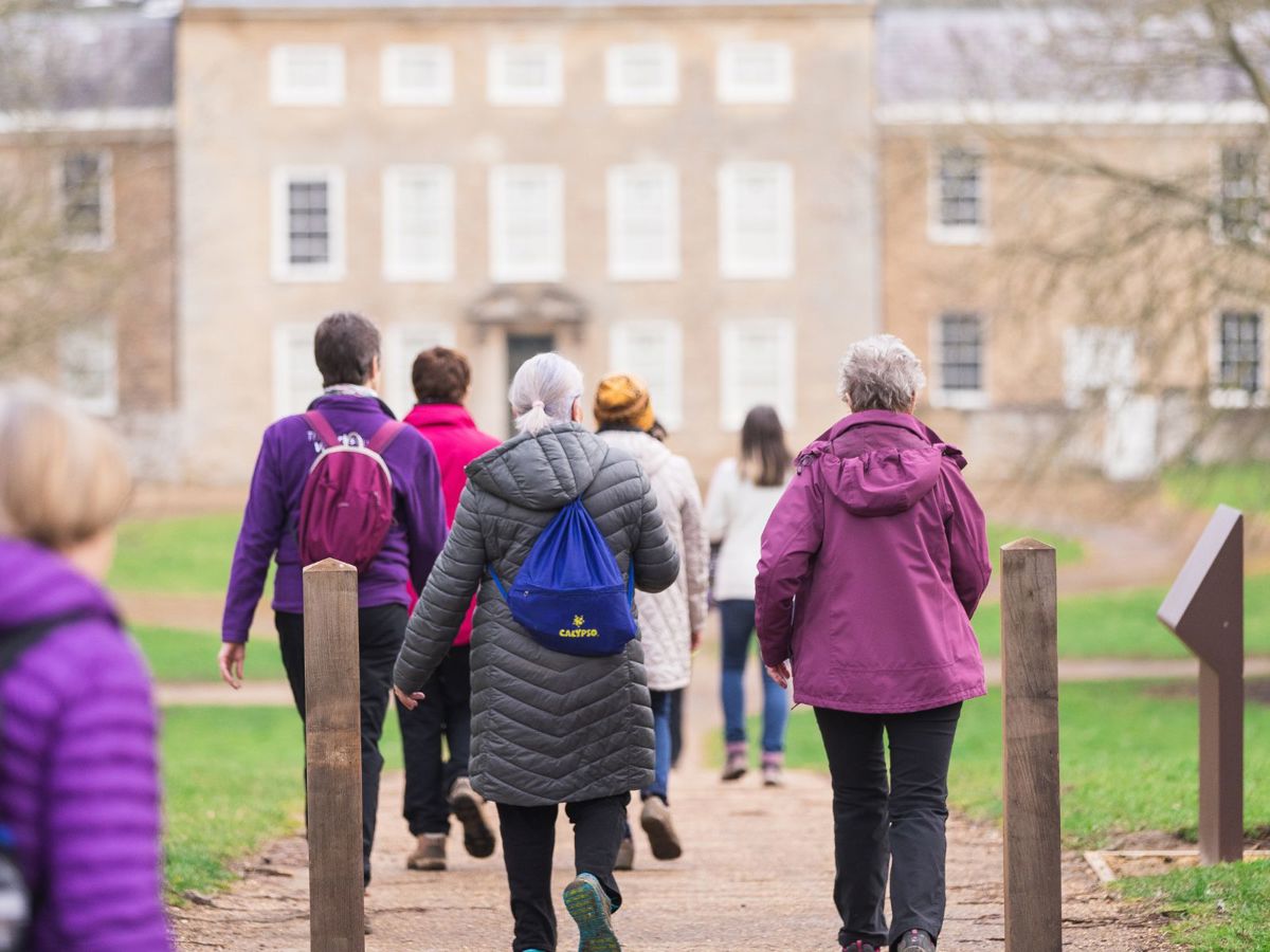 Group of people walking through Great Linford Manor Park towards Manor house