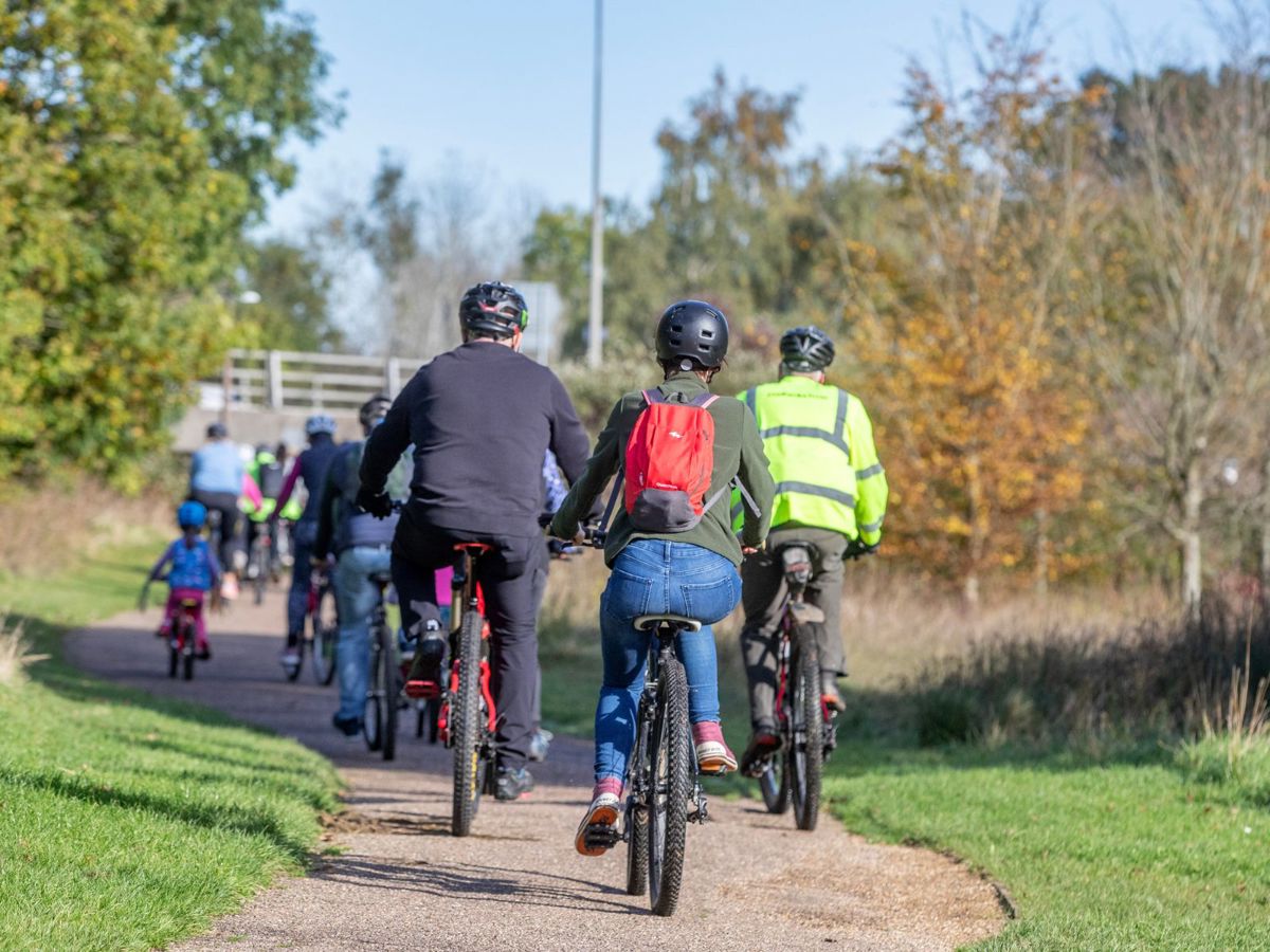 Group of people cycling down pathway in the park