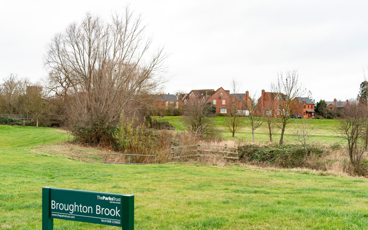 Houses, pond and park sign at Broughton Brook. 